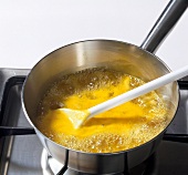 Orange syrup is being boiled in pot