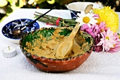 Avocado body wrap in bowl with wooden spoon and flowers