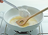 Flour being added with spoon in liquid butter