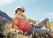 Beautiful woman wearing beret and sunglasses relaxing on meadow