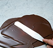 Melted chocolate being spread with spatula for chocolate curls, step 1