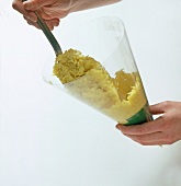 Yellow turmeric rice being filled in cornet with spoon, step 2