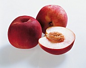 Whole and halved peaches on white background