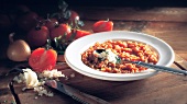 Tomato risotto on plate beside tomatoes and onions