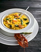 Saffron risotto with asparagus on plate beside crayfish