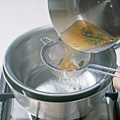 White wine with herbs being poured in bowl through sieve, step 5