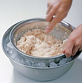 Close-up of hand stirring cream and pike meat in bowl, step 6