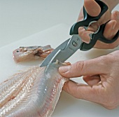 Close-up of hand cutting fish for roe, step 4