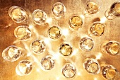 Wine glasses filled with white wine on golden surface, overhead view