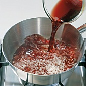 Red wine being poured in pan with chopped shallots, step 1
