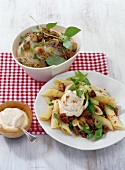Rice noodles in bowl and penne with mince and yogurt on plate