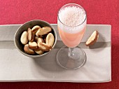 A bellini next to a dish of Brazil nuts