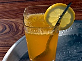Apricot fizz drink in glass with lemon slice on rim