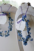Wreath made of blue flowers with name tags hung on back of chair