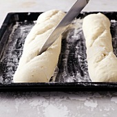 Close-up of bread dough being cut with knife