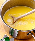 Close-up of yeast in milk with butter in pot with spoon