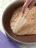 Close-up of hand spreading smooth mixture on baked bread, step 1