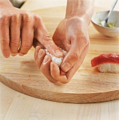 Sushi - Reisklößchen auf Fischsc heibe setzen