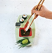 Sushi - Sushi wird mit Esstäbche n in Sojasoße getaucht