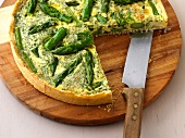 Quiche with green asparagus on wooden board