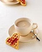 Heart shaped waffle with cup of coffee on saucer