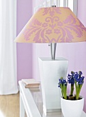 Lampe m. floralem Muster auf einer Konsole, Bücher, Blume