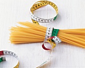 Raw spaghetti tied together with measuring tape