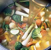 Close-up of water being poured in vegetables sauteed with butter, step 2