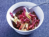 Red cabbage and cranberry salad with apples and walnuts in bowl with spoon