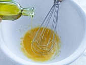 Olive oil being poured in egg yolk for preparation of cauliflower salad, step 2