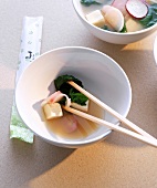 Miso soup with tofu, spinach, radishes and chopsticks in bowl