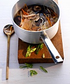 Ramen noodles with pork, carrots and mushroom in sauce pan