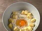 Mixture of flour, sugar, egg and butter in bowl for preparation of biscuits, step 1