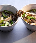 Two bowl of soba noodles with fish soup, saithe and asparagus