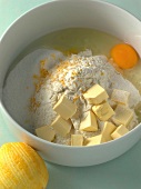 Peeled orange, butter, flour and egg in bowl for preparation of biscuits, step 1