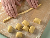 Close-up of hand forming strands of dough for preparation of biscuits, step 3