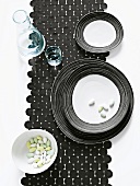 Table runner of wool felt black circles with glass, carafe and bowl on it