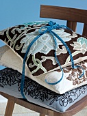 Blue and brown floral pattern cushions tied together on wooden chair