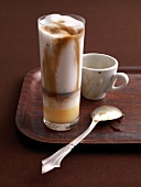 Glass of solccino, coffee cup and spoon on tray