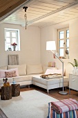 Weißes Sofa, weißer Teppich, Fenster , Holzdecke, Baumstämme als Tische