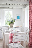 Red and white checked curtains and tablecloth, laid dining table and kitchen counter