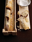Puff pastry with filling and icing sugar on wooden serving dish
