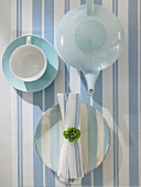 Close-up of teacup, teapot and striped plates on striped tablecloth