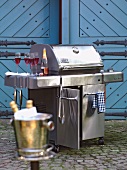 Large stainless steel grill with red champagne bottle and glasses in outdoors