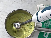 Green sauce being mixed with hand blender for preparation of sauce