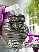 Welcome' and 'Home sweet home' written on wooden heart hanging on chair