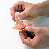 Close-up of hand removing shell of shrimp, step 4