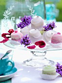Mini cakes on a cake stand decorated with candied and fresh flowers