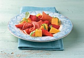 Strawberry and mango salad with parma ham on plate