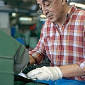 Man carrying out grinding process during blade manufacturing, Swabia, Germany